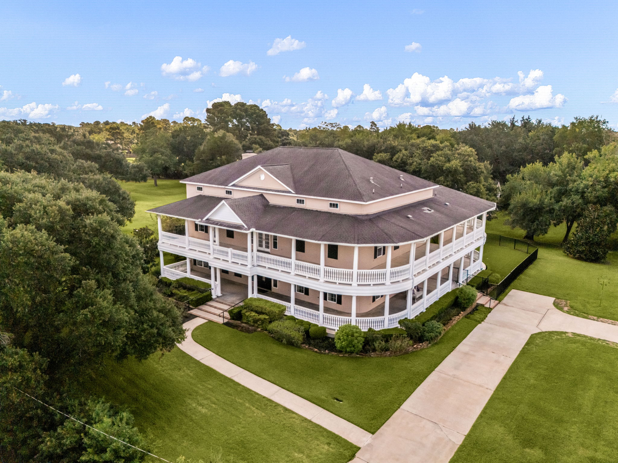 Two-story Southern-style home in Old Katy, TX with wraparound porches on both levels, surrounded by mature trees on a 2.46-acre lot