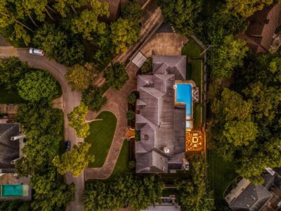 Aerial night view of the property showcasing the illuminated pool, fire pit seating area, and expansive landscaped backyard.