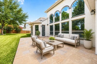 Home for sale in Aliana with a spacious stamped-concrete patio framed by dramatic two-story arched windows, offering a versatile outdoor space for dining, entertaining, or relaxing. Virtually staged.