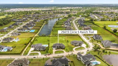 A covered outdoor living area with a gas-connection kitchen opens onto the professionally landscaped backyard, with the automatic gated drive and oversized garages framing the front of the home.