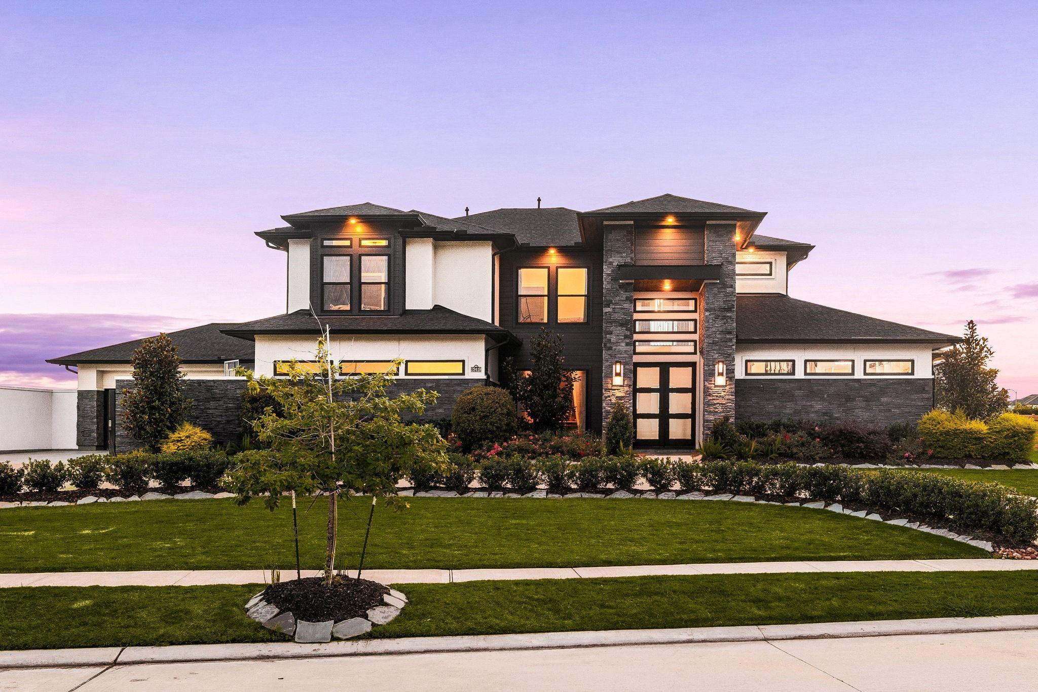 Twilight exterior of contemporary home in Fulshear Run with stone accents and covered entry