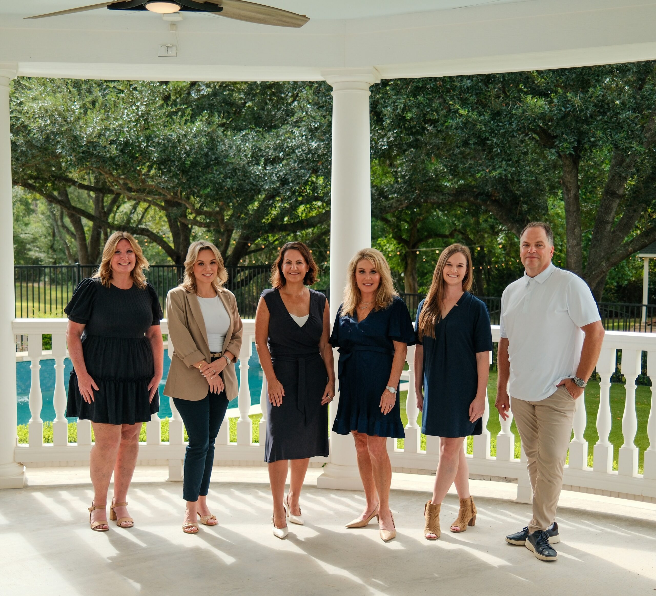 The Jamie McMartin Group, a Compass real estate team, standing in a white gazebo with oak trees behind them, ready to help Katy home sellers navigate mortgage rates above 7%